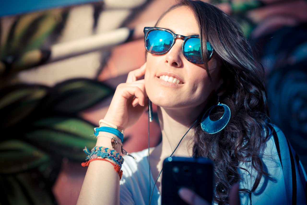 young beautiful brunette woman with smart phone listening music in the city